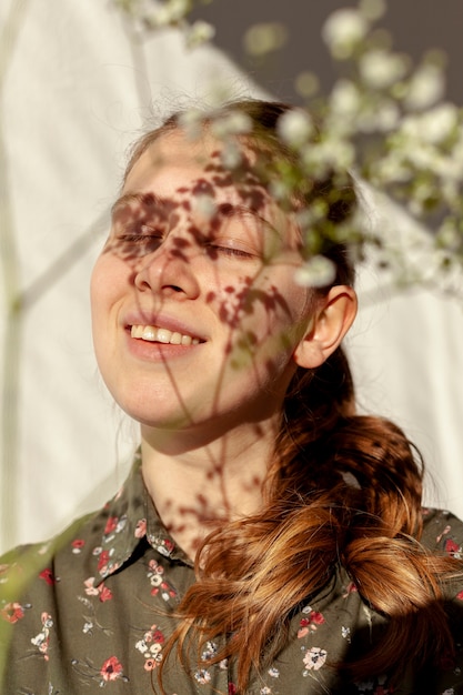 Photo gratuite modèle heureux avec des fleurs défocalisées