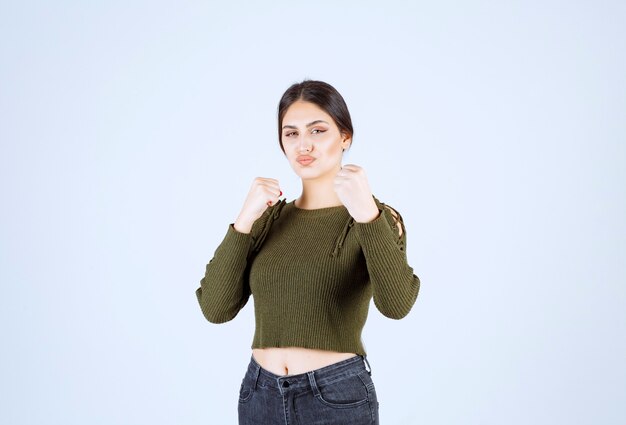 Un modèle de jeune femme charmante en vert montrant comment frapper