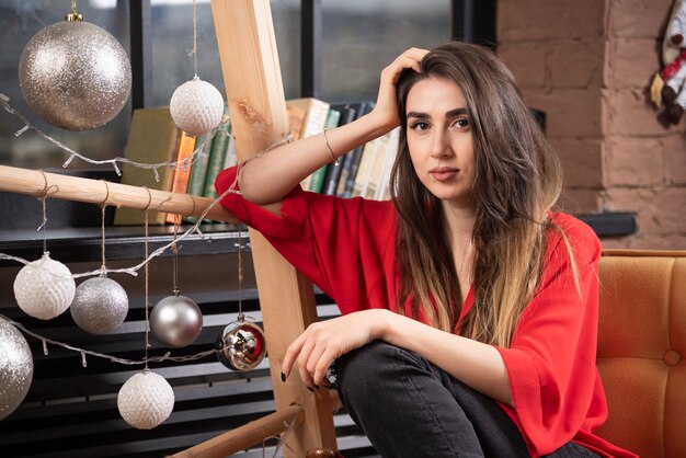 Un modèle de jeune femme en chemisier rouge assis et posant.