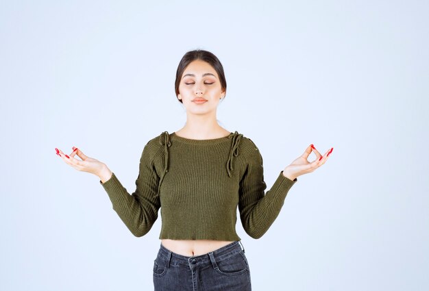 Un modèle de jeune femme détendue debout et méditant.