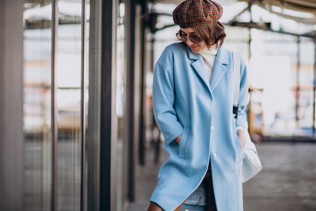 Modèle de jeune femme en manteau bleu par le café