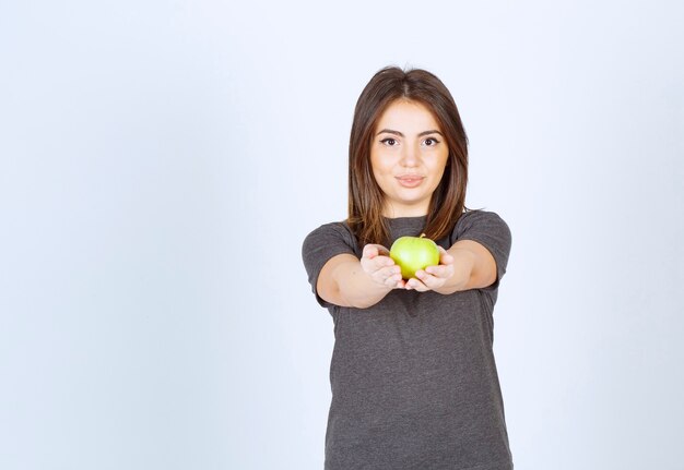 modèle de jeune femme offrant une pomme verte.