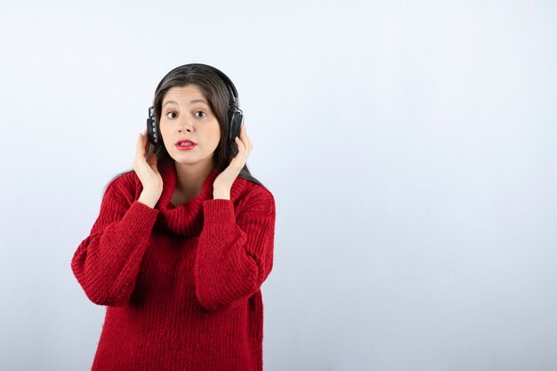 Modèle de jeune femme en pull rouge tenant des écouteurs