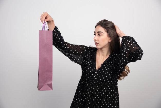 Modèle de jeune femme à la recherche sur un sac à provisions vide