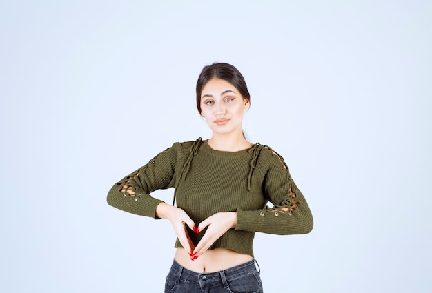 Photo gratuite modèle de jeune femme souriante faisant coeur avec les doigts.