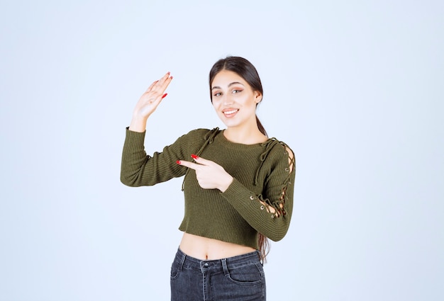 modèle de jeune femme souriante montrant un panneau d'arrêt et pointant vers l'extérieur.