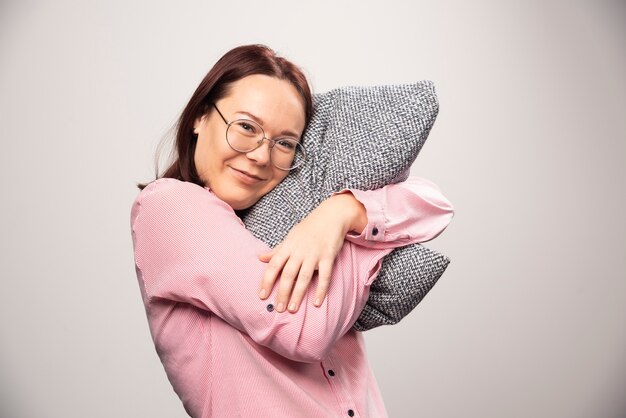 Modèle de jeune femme tenant un oreiller sur fond blanc. Photo de haute qualité