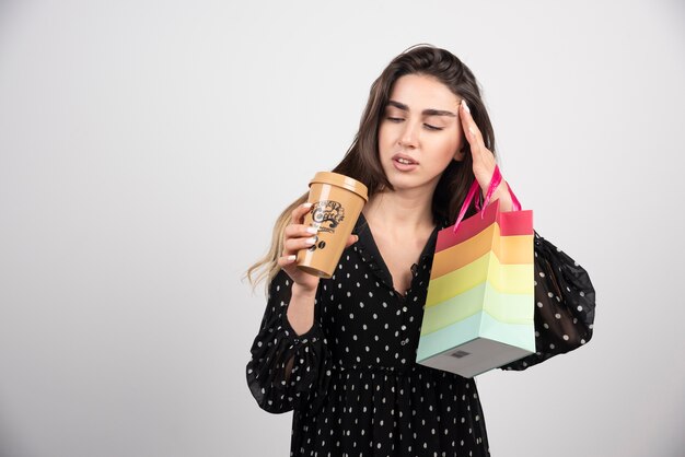 Modèle de jeune femme tenant un sac de magasin avec une tasse de café