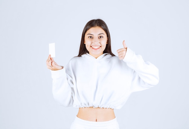 modèle de jeune fille heureuse avec une carte montrant un pouce vers le haut.