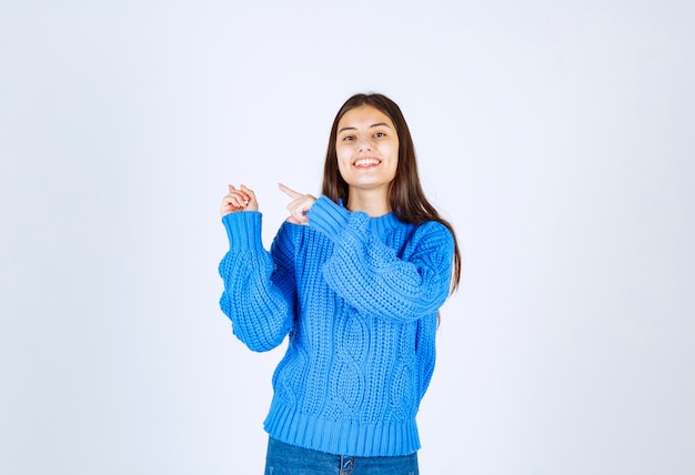 modèle de jeune fille pointant vers le mur blanc.