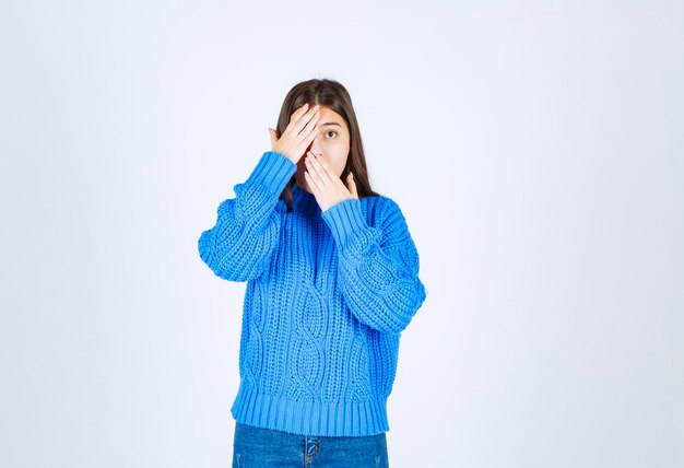 modèle de jeune fille en pull bleu coning eye avec une main sur blanc-gris.