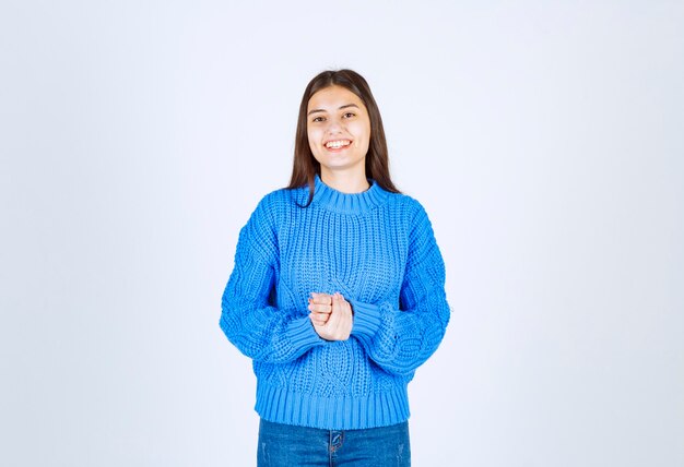 modèle de jeune fille en pull bleu debout et posant sur blanc-gris.