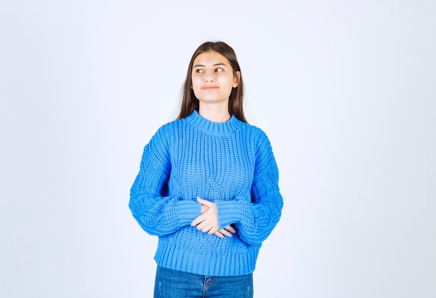 modèle de jeune fille en pull bleu debout et posant sur blanc-gris.