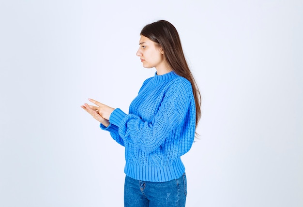 modèle de jeune fille en pull bleu debout et posant sur blanc-gris.