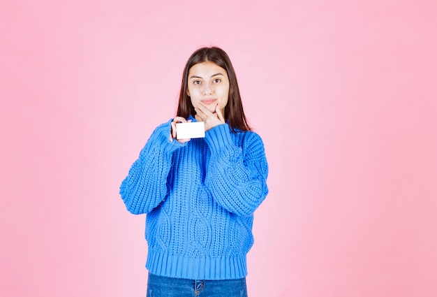 modèle de jeune fille tenant une carte sur le mur rose.