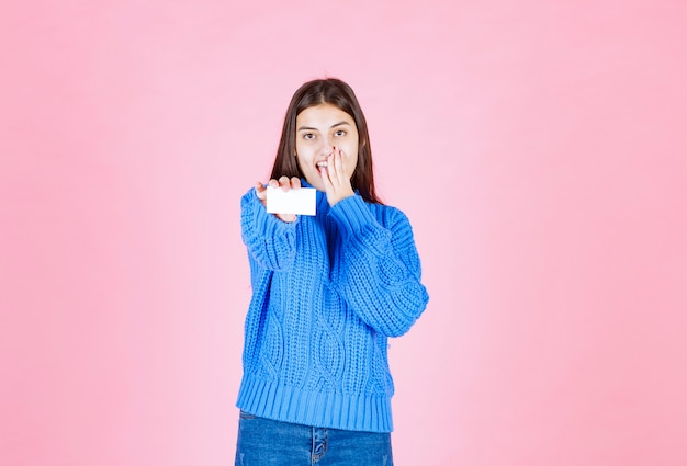 modèle de jeune fille tenant une carte sur le mur rose.