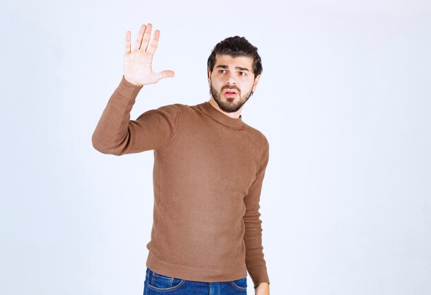 Un modèle de jeune homme beau regardant loin et levant la main.