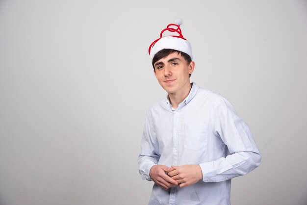 Modèle de jeune homme séduisant debout dans un chapeau de Noël et regardant la caméra