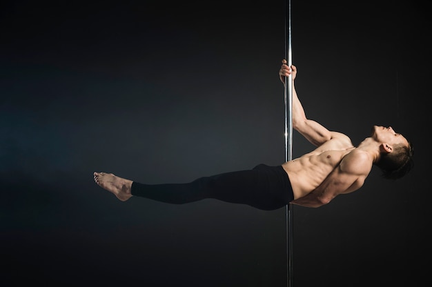 Modèle masculin attrayant effectuant une pole dance