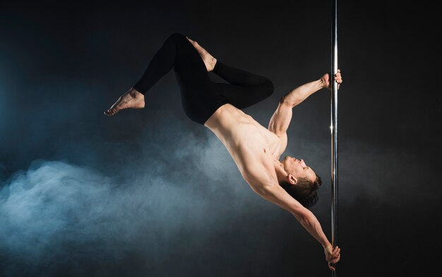 Modèle masculin attrayant effectuant une pole dance