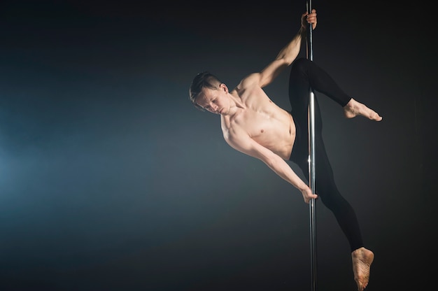 Modèle masculin attrayant effectuant une pole dance