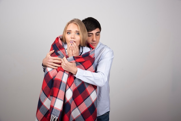 Modèle de mec brune couvrant une femme blonde avec une couverture à carreaux