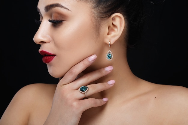 Le modèle montre des boucles d&#39;oreilles et une bague avec de belles pierres précieuses bleues