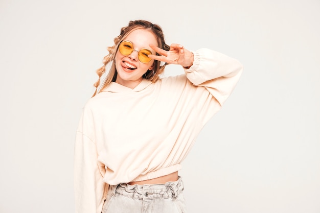 Modèle positif et drôle posant sur un mur gris en studio à lunettes de soleil