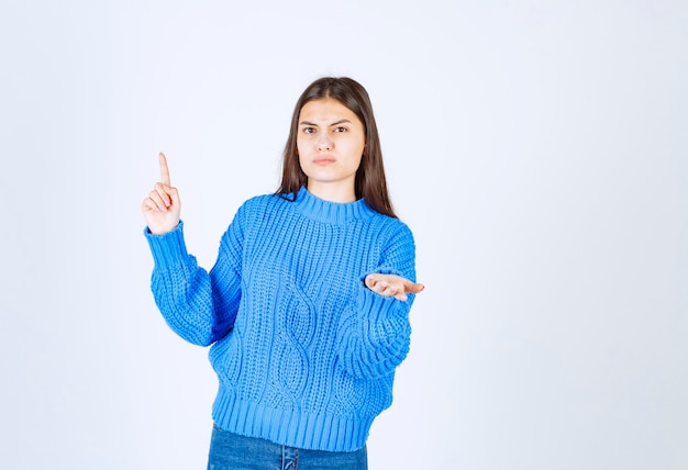 modèle sérieux de jeune fille pointant vers le haut.