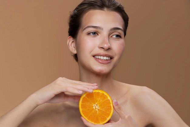 Photo gratuite modèle smiley vue de face posant avec orange