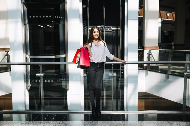 Modèle souriant avec achats dans le centre commercial