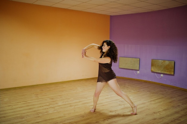 Photo gratuite modèle de taille plus brune bouclée faisant des acrobaties à la salle de danse