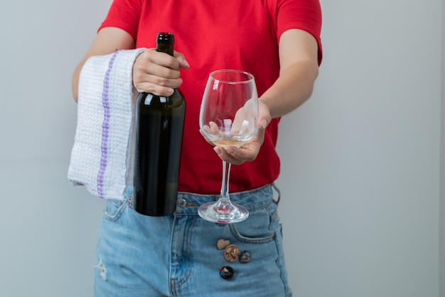 Un modèle tenant une bouteille de vin et un verre