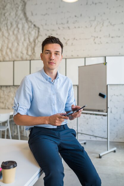 Moderne jeune homme souriant élégant dans le bureau de co-working, pigiste de démarrage tenant à l'aide de la tablette,