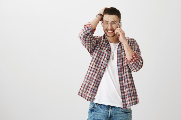 Modeste beau jeune homme posant avec son téléphone