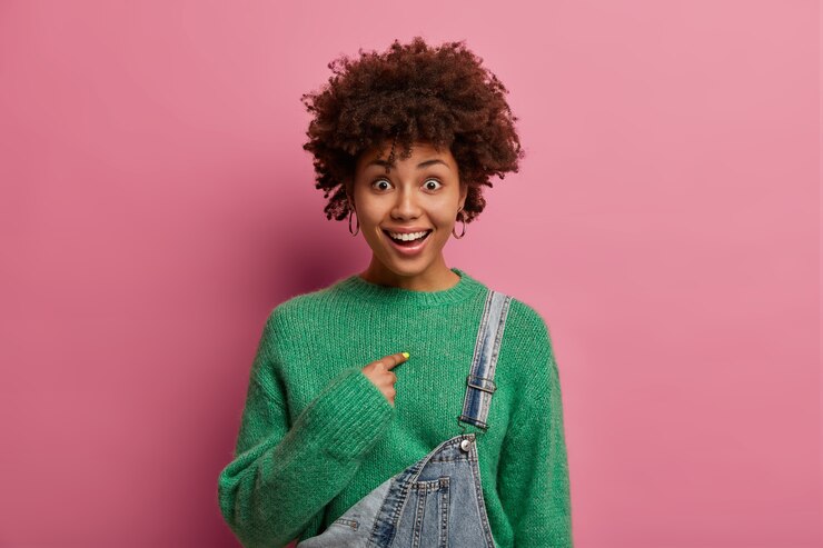 Photo gratuit une modeste femme surprise et heureuse vous demande de parler de moi, se montre du doigt