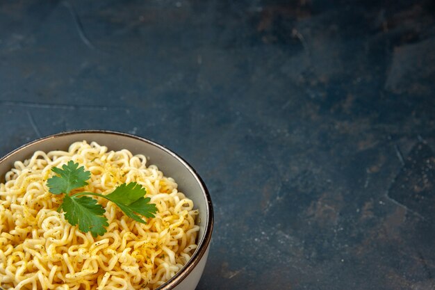 La moitié inférieure des nouilles ramen avec de la coriandre dans un bol sur une table sombre avec un espace libre