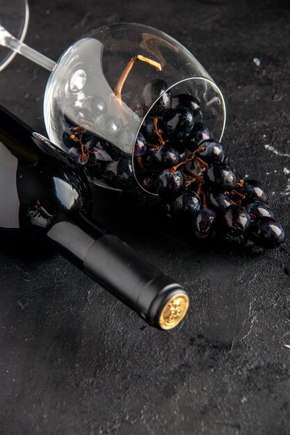 La moitié inférieure vue bouteille de vin verre à vin renversé raisins noirs