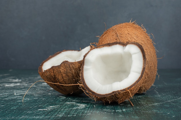 Photo gratuite la moitié des noix de coco coupées et entières sur table en marbre