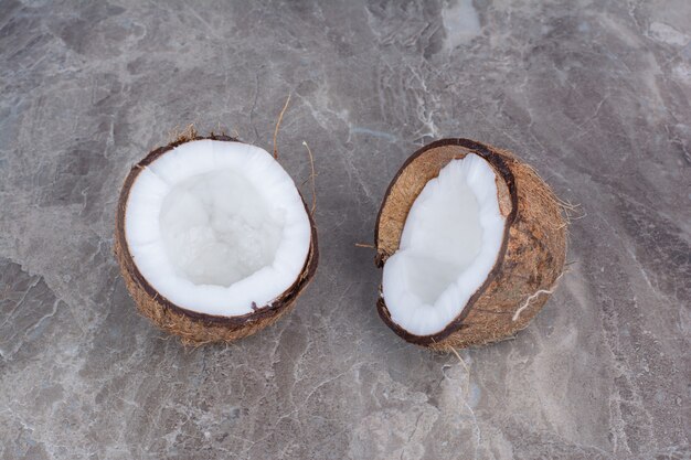 La moitié des noix de coco fraîches coupées sur fond de pierre.