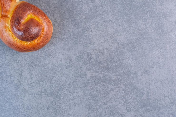 Photo gratuit la moitié d'un petit pain sucré tourbillonnant sur fond de marbre. photo de haute qualité