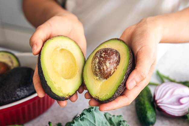 Photo gratuite moitiés d'avocat dans une main féminine dans la cuisine