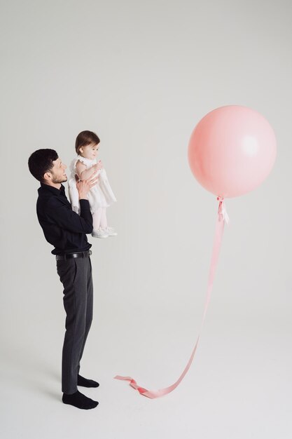 Moment père fille regardant un ballon rose sur fond blanc