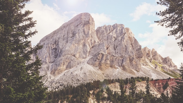 Montagne brune près des arbres verts sous un ciel nuageux ensoleillé blanc et bleu