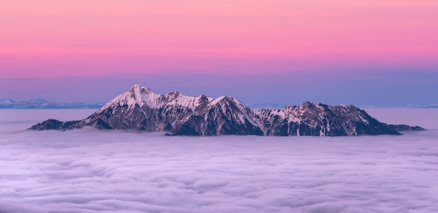 montagne enneigée entourée de mer de nuages