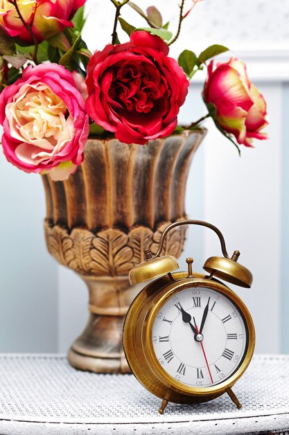 montre horloge classique dans un intérieur rétro coloré lumineux derrière des fleurs rouges