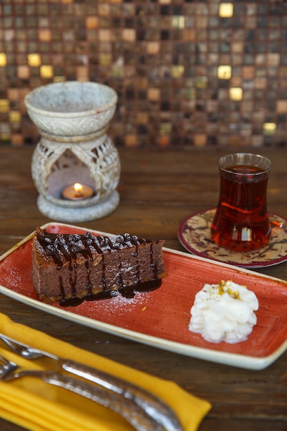 Un morceau de brownie au chocolat servi avec de la crème et du thé