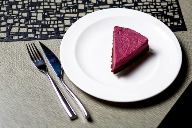 Un morceau de gâteau au fromage aux framboises en plaque blanche servi sur la table