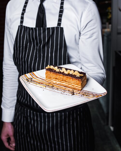 Morceau de gâteau avec glaçage au chocolat et arachides sur le dessus