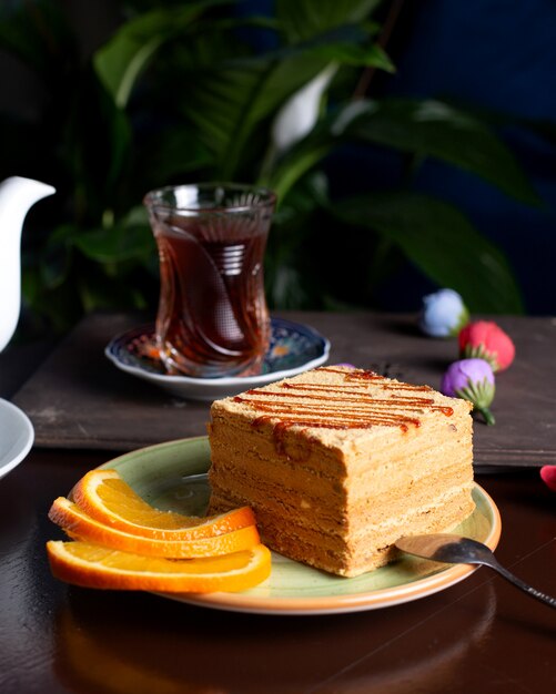 Morceau de gâteau servi avec des tranches d'orange servi avec du thé